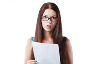 A shocked-looking woman reads a letter containing bad news. Photo via Shutterstock