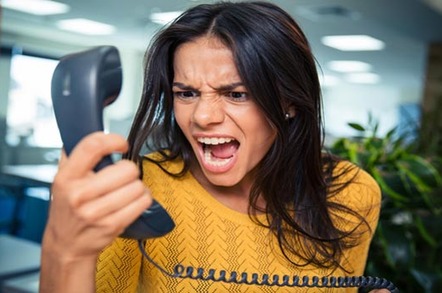 Angry businesswoman shouting on phone in office. Image via Shutterstock