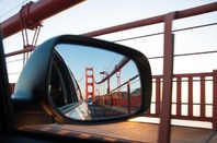 A view of the Golden Gate Bridge at sunset from the rear view mirror of a car. Pic via Shutterstock