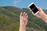 Hiker checks dead battery on smartphone... against wild valley backdrop. Photo via Shutterstock