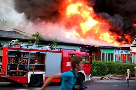 Man runs as a fire engine pulls up to a burning building. Pic by Shutterstock