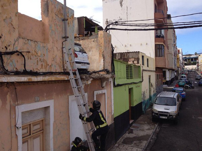 A fireman scales a ladder to the car parked on a first-floor rooftop