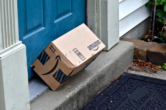 Amazon box tipped over, propped against doorframe.Photo by Jeramey Lende via Shutterstock