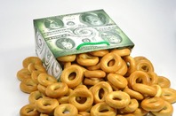 Bread/pretzels in the shape of zeros tumble out of a paper packet. photo via sHutterstock