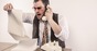 Angry man yelling on phone while reading vintage printer paper report. Photo by SHutterstock