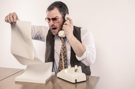 Angry man yelling on phone while reading vintage printer paper report. Photo by SHutterstock