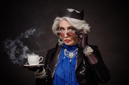 Woman in tiara posing with cup of tea, crown and jewels
