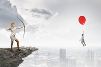 Businesswoman shoots arrow from cliff at balloon holding up rival... Bit silly conceptual art. Photo by Shutterstock