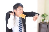 Man eats toast while looking at watch, clearly late for something. Photo by Shutterstock