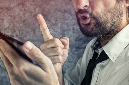 A man talks angrily into his mobile. Photo via Shutterstock