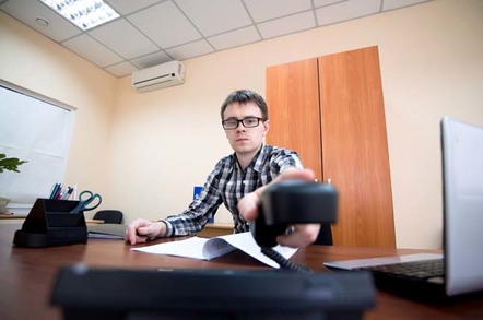 Man hangs up desk phone after a clearly irritating call. Photo by Shutterstock