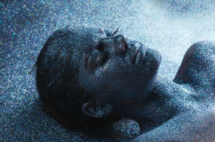 "New and shiny" person lies with eyes closed, covered in grey glitter. Photo by Shutterstock