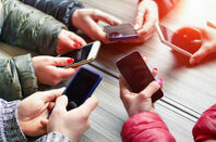 A group of people hold out mobile phones in a circle. Photo by Shutterstock