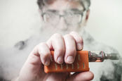 Man with a vaper apparatus - face obscured by smoke/vapour. Photo by Shutterstock
