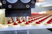 Conveyor belt production of jam-topped biscuits. Photo by Shutterstock