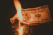 Burning money, photo via Shutterstock