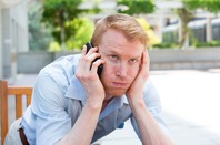 Man exasperated after being on hold for a long period of time. Photo by Shutterstock