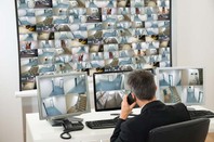 Security guard watches footage from hundreds of camera. Photo by Shutterstock