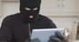 Burglar sits in kitchen with stolen tablet. Photo by Shutterstock