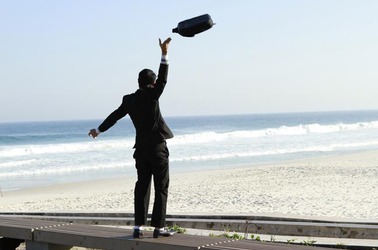 Man throws briefcase in the air happily on the beach. Photo by Shutterstock