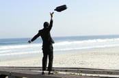 Man throws briefcase in the air happily on the beach. Photo by Shutterstock