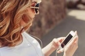 Woman uses headphones with her iPhone. Photo by Shutterstock