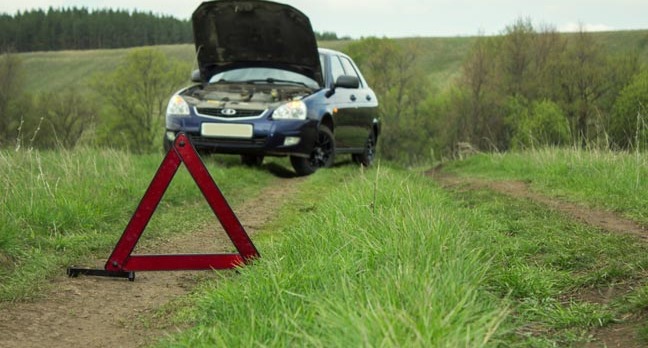 A car pulled over near a hazard sign on a country road. Photo by Shutterstock