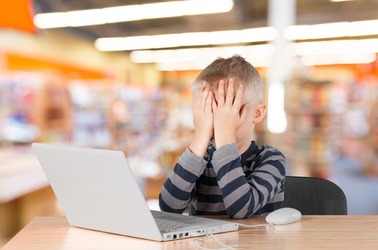 Child in shock in front of computer. Photo by Shutterstock