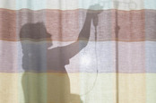 Nurse erects drip behind privacy curtain at hospital bed. Photo by Shutterstock