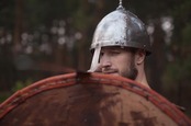 Man in helmet looks uncertain, holds up shield. Photo by Shutterstock