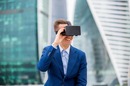 Smiling man wears VR headset against backdrop of city. Photo by Shutterstock