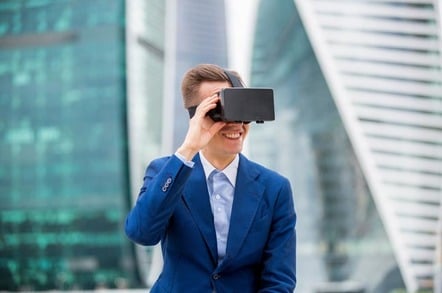 Smiling man wears VR headset against backdrop of city. Photo by Shutterstock