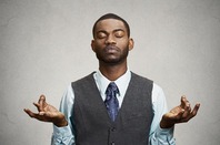 Suit-and-tie-wearing man tries to meditate, take deep breaths in faux yoga pose. Photo by Shutterstock
