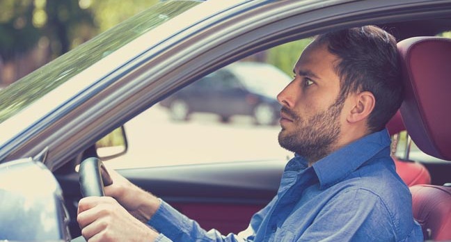 Terrified man clutches steering wheel of car. Photo by shutterstock