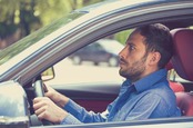 Terrified man clutches steering wheel of car. Photo by shutterstock