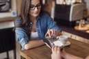 Woman uses card reader at coffeee shop. Photo by Shutterstock