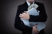 man in suit clutches briefcase full of cash. Photo by Shutterstock