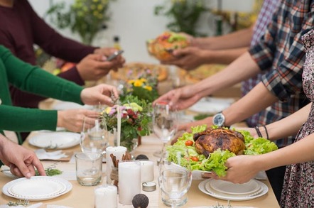 People sit down to a meal at a table. Photo by Shutterstock