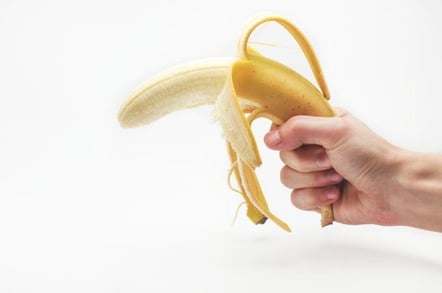 Man holds banana like a gun. Photo by Shutterstock