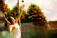 Woman serves at beginning of tennis game. Photo by Shutterstock