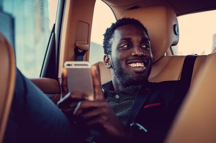 Passenger in back of cab using smartphone app/cab app. Photo by Shutterstock