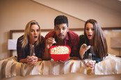 Friends look shocked watching TV. photo by Shutterstock