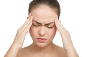 woman winces in pain rubs temples - headache