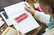 person opens letter reading 'banned'