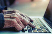 Old man's hands typing on laptop
