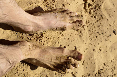 Feet on hot beach sand