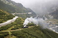 Train in the Alps emerges from clouds. Photo by Shutterstock