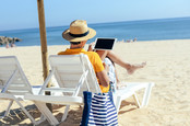 Man browses his tablet and ignores the beach. Photo by shutterstock