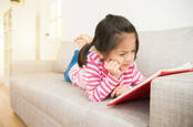 Little girl concentrates hard on a book she's reading
