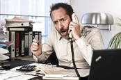 Upset man at desk shouts into phone. Pic: Shutterstock